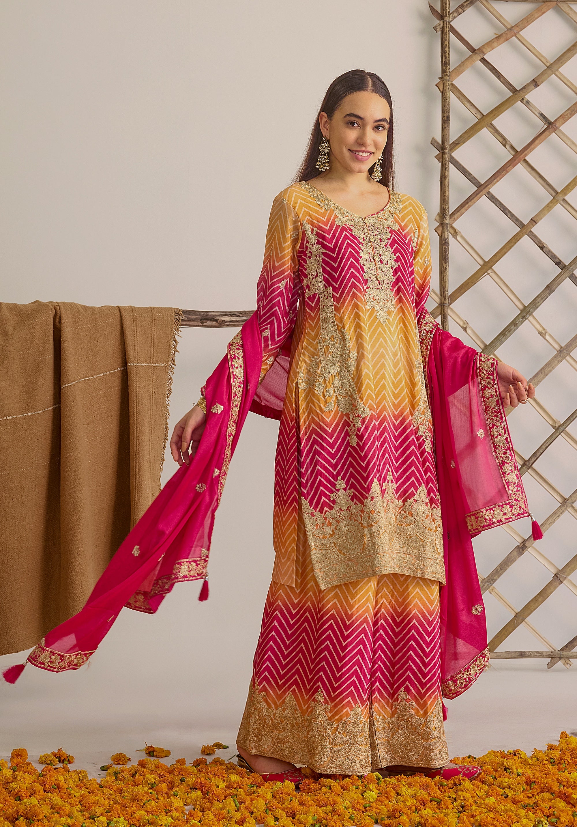 Gradient yellow pink Ira suit Indian ethnic wear: premium chiffon silk with gold floral embroidery, leheriya palazzo gold borders, ethereal tassel dupatta, buy salwar kameez online for festive grace.