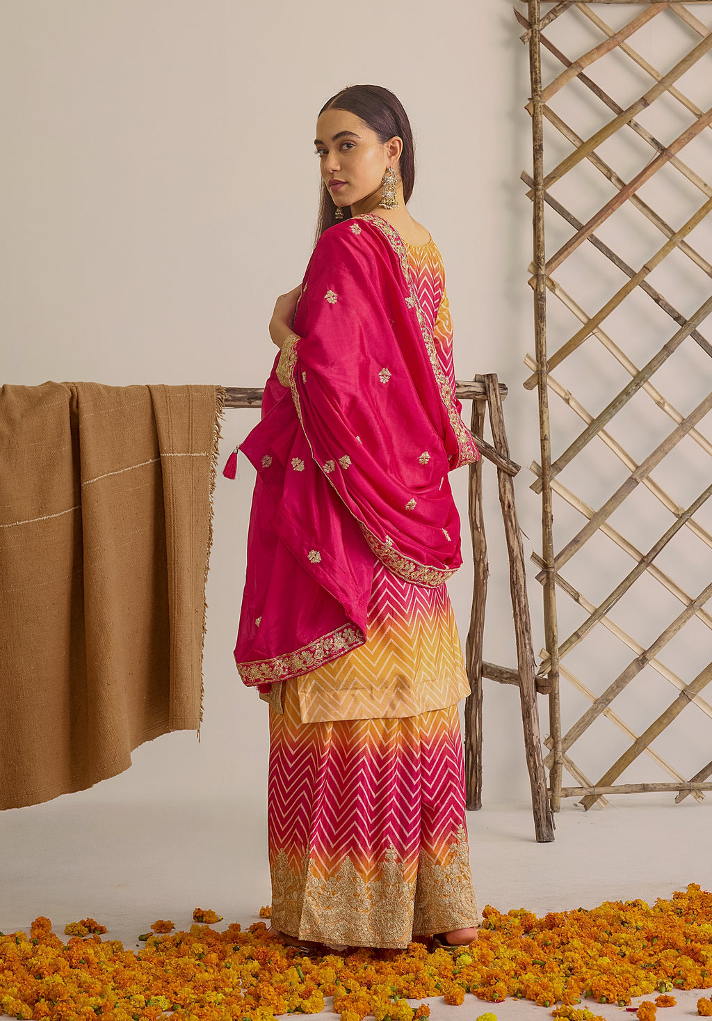 Gradient yellow pink Ira suit Indian ethnic wear: premium chiffon silk with gold floral embroidery, leheriya palazzo gold borders, ethereal tassel dupatta, buy salwar kameez online for festive grace.